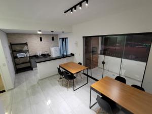 a kitchen with wooden tables and chairs in a room at Sapucaia Flat - Apart Hotel in Santa Rita do Sapucaí