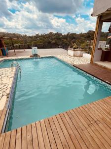 a large swimming pool with a wooden deck at Chácara Com Piscina e Vista das Montanhas in Atibaia