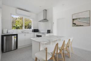 a kitchen with white cabinets and a table and chairs at Peaceful 2-Bed Apartment in Coastal McCrae in McCrae