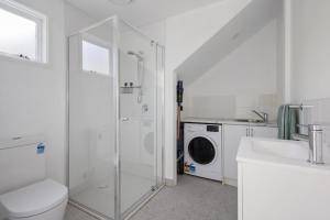 a white bathroom with a shower and a washing machine at Peaceful 2-Bed Apartment in Coastal McCrae in McCrae
