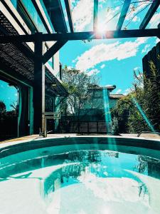 a swimming pool in a house with the sun shining at Sheeps Family - Loft, Casa e Apartamento para Temporada - Praia do Rosa in Praia do Rosa