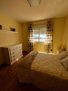 een slaapkamer met een bed, een ladekast en een raam bij Apartamento vital centrico in Lanjarón