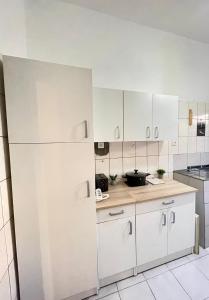 Una cocina con gabinetes blancos y un refrigerador blanco. en JAMARI Home, en Bonabéri
