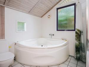 a white bathroom with a tub and a toilet at Bright Beach House with Sauna - By Traum Ferienwohnungen in Vejers Strand
