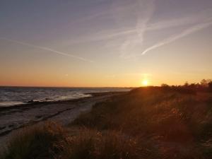 einen Sonnenuntergang am Strand mit Sonnenuntergang in der Unterkunft 10 person holiday home in Væggerløse in Bøtø By