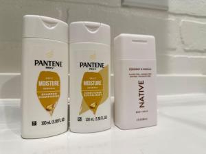 Drei weiße Flaschen mit Musice-Feuchtigkeitspflegeprodukten auf einer Theke in der Unterkunft Gorgeous loft downtownSherman washer dryer WiFi in Sherman + 1 Foto