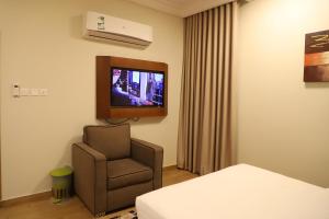 Cette chambre dispose d'une chaise et d'une télévision murale. dans l'établissement Taraf Yanbu 2, à Yanbu