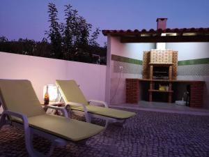 two chairs sitting on a patio with a fireplace at Quiaios Beach House in Quiaios