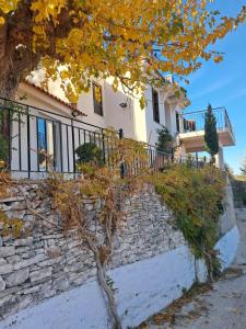 a large white house with a stone wall at Akros-cottage on mountain- ground floor in Stavrinídes