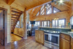 eine Küche in einem Blockhaus mit einem großen Fenster in der Unterkunft Serenity Now Cabin with Fire Pit and Game Room! in Logan