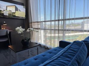 Una sala de estar con un sofá azul y una ventana grande. en Quest Henderson, Auckland Apartment Hotel, en Auckland