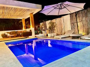 a swimming pool with an umbrella and a couch at Casa Kai in Palomino
