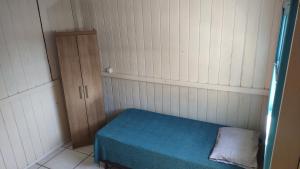 a small room with a bed and a cabinet at Casa de Boneca perto da praia in Imbituba