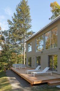 a house with a deck and benches on it at Maison Solus - Mont Tremblant in Lac-Superieur