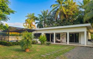 una casa blanca con palmeras en el fondo en Pura Vida - Villa Elenita, en Parrita