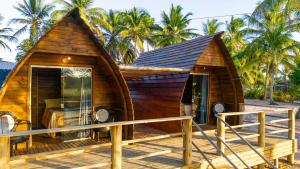 une petite maison en bois sur une terrasse avec des palmiers dans l'établissement Bangalôs na beira do rio e a poucos metros do mar, à Belmonte