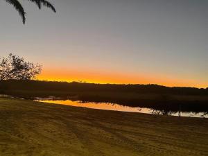 - un coucher de soleil sur une étendue d'eau avec une plage dans l'établissement Bangalôs na beira do rio e a poucos metros do mar, à Belmonte