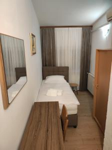 a room with a bed and a table and a mirror at Rooms San in Velika Gorica