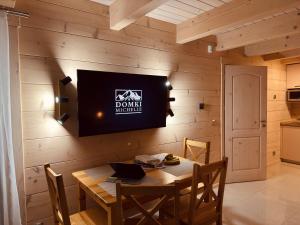 a dining room with a table and a tv on a wall at Domki Michelle in Wisła