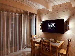 a dining room with a table and a tv on a wall at Domki Michelle in Wisła