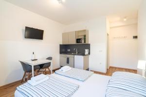 1 dormitorio con 2 camas, escritorio y cocina en Alps Studio, en Innsbruck