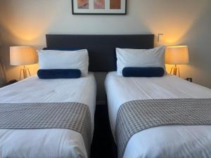 Dos camas una al lado de la otra en una habitación. en Quest Henderson, Auckland Apartment Hotel, en Auckland