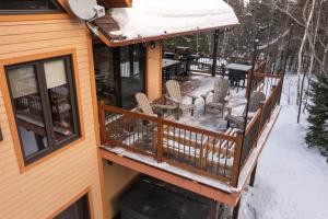a deck with chairs and a table in the snow at Au Grand Merisier : Chalet alpin in Petite-Rivière-Saint-François
