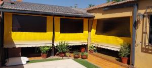 ein gelbes Haus mit Topfpflanzen im Innenhof in der Unterkunft La Emilia Casa de Vacaciones con Pileta y Quincho in Salta