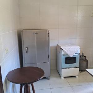a kitchen with a refrigerator and a table and a microwave at Suíte Descanso na Serra in Campos do Jordão