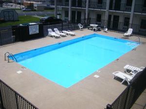 a large blue swimming pool with chairs and tables at Travelers Inn Elizabethton in Elizabethton