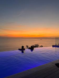 a swimming pool with a view of the ocean at sunset at Bluerama - Adults Only in Haad Pleayleam