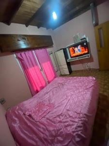 ein Schlafzimmer mit einem rosa Bett und einem TV in der Unterkunft Florencia in Miramar