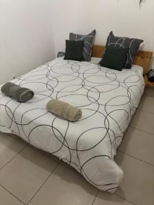 a large bed with black and white sheets and pillows at Saka Lodge in Le Gosier