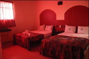 two beds in a room with red walls and windows at J Alejandro - Centro Histórico Guadalajara in Guadalajara