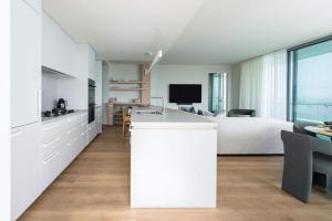 a white bedroom with a bed and a kitchen at Monet by Khove - Kirra Beach in Gold Coast