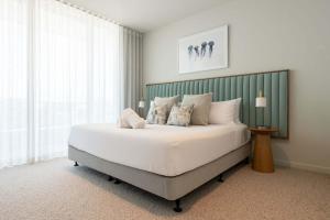 a bedroom with a large white bed with a green headboard at Monet by Khove - Kirra Beach in Gold Coast