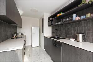 Una cocina con un refrigerador blanco y gabinetes grises. en City Escape with Spa Access in Darlinghurst, en Sídney
