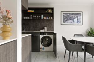 una cocina con lavadora y mesa en City Escape with Spa Access in Darlinghurst, en Sídney