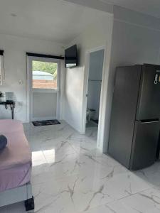 a living room with a large tile floor and a refrigerator at Sharnyta's Studio Aitutaki in Amuri