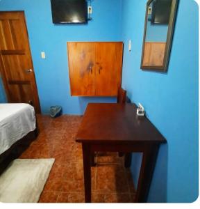 une pièce avec une table en bois et un mur bleu dans l'établissement Hostal Fernánda, à Corn Island