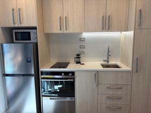 a kitchen with a stove and a sink and a refrigerator at Central City Prime-next to SKY in Auckland