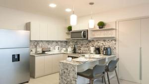 a kitchen with a counter with chairs and a refrigerator at Modern 1-BR with Park & Ocean Vistas in Panama City in Panama City
