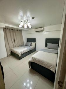 a bedroom with two beds and a chandelier at Shell Residence 2 bedroom by Kathy in Manila +39 photos