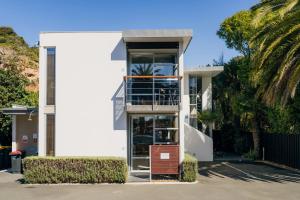una casa blanca con una palmera en Sumner Bay Motel, en Christchurch