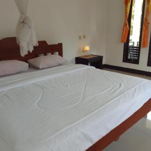 a large white bed in a white bedroom at Shila Bungalow in Kelimutu