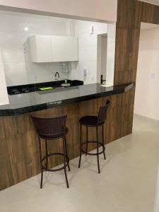 una cocina con 2 taburetes y una barra en Apto 2 qtos perto do Aeroporto, próximo ao CRER, en Goiânia 4 fotos más