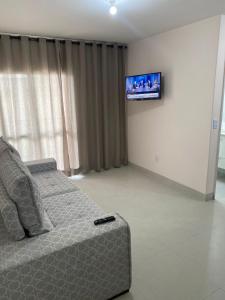 Una sala de estar con un sofá y un televisor de pantalla plana. en Apto 2 qtos perto do Aeroporto, próximo ao CRER, en Goiânia