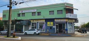 a green building with a car parked in front of it at Hotel Pasettus in Bela Vista do Paraíso