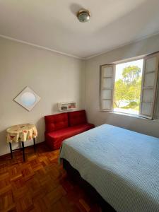 sypialnia z łóżkiem i czerwoną kanapą w obiekcie Apartamento 122 no Condomínio Quisisana w mieście Poços de Caldas