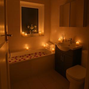 La salle de bains est pourvue d'une baignoire, d'un lavabo et de bougies. dans l'établissement The Bliss House Peaceful Retreat Close Transport Links Central London in 15mins Close to Heathrow Airport, à Harrow on the Hill